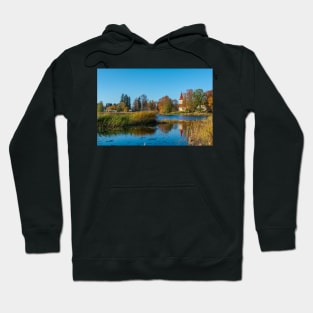 Church standing on the calm lake shore in sunny day Hoodie